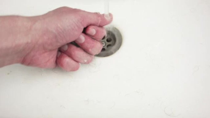 一个男人刮胡子后清理水槽。一只手的特写。