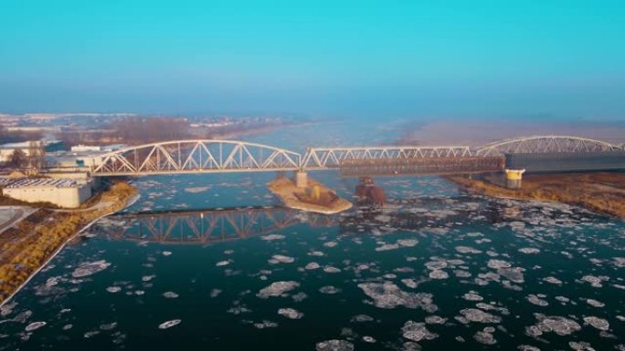 雾蒙蒙的冬天早晨，浮冰在火车桥附近的冬季冰冻河上漂流，用于货运