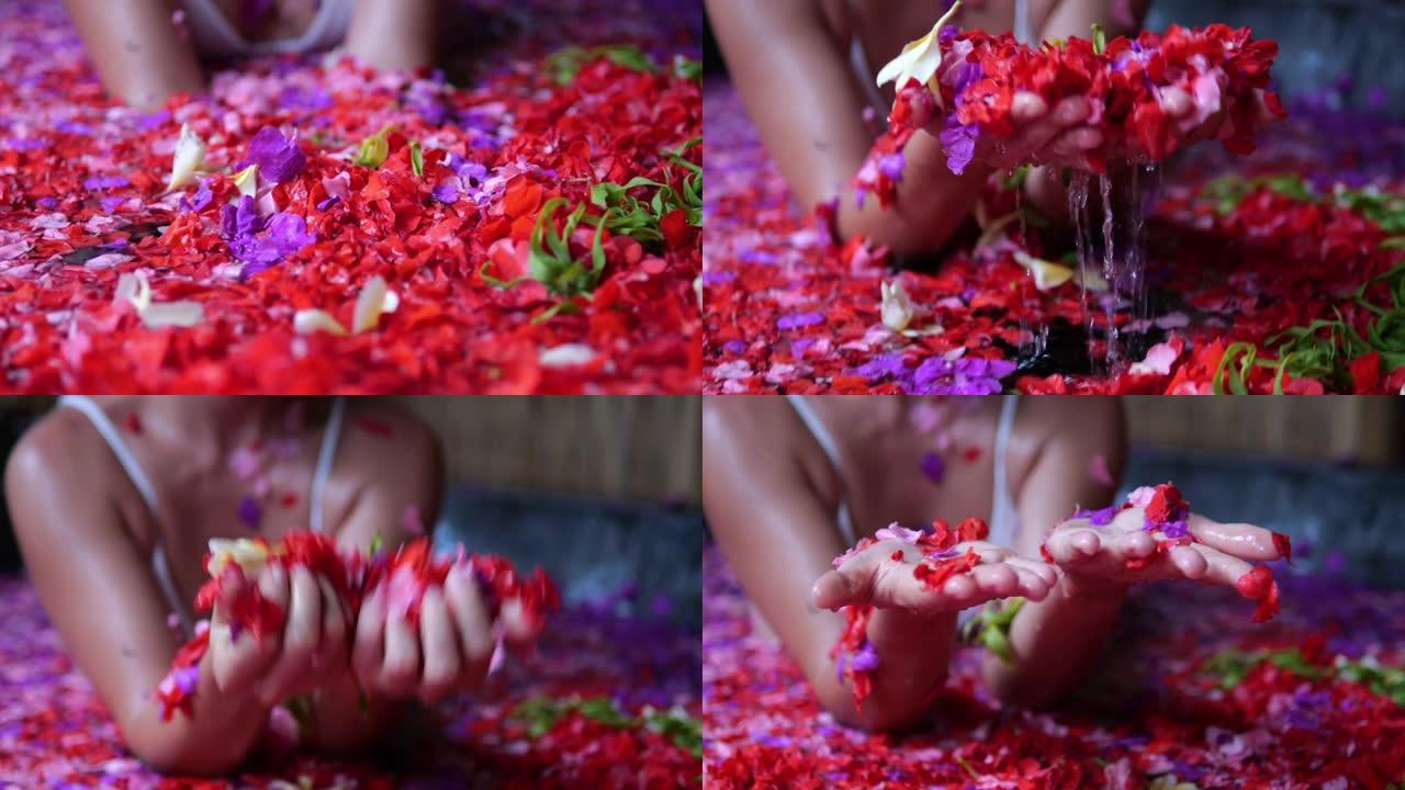 一个女人在温泉旅馆里放松，浴缸里有红色和粉红色的花朵。鲜花芳香疗法概念。在巴厘岛的一家天堂酒店度假时