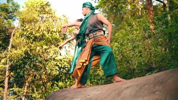 一名亚洲男女在森林中央穿着绿色衣服在岩石上跳舞