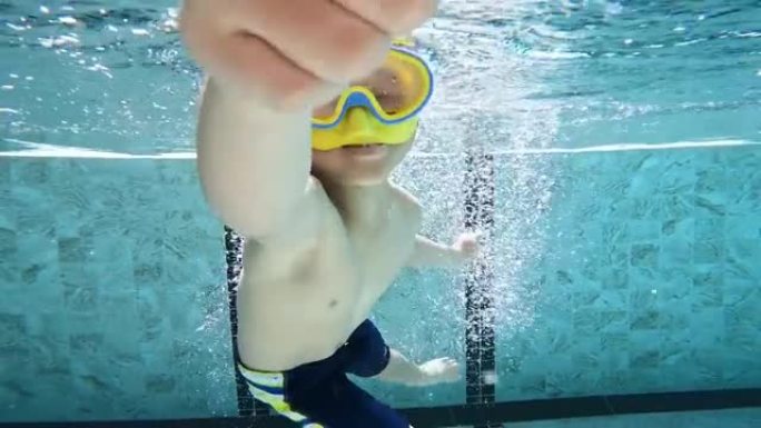 亚洲男孩在游泳池的水下玩耍和游泳