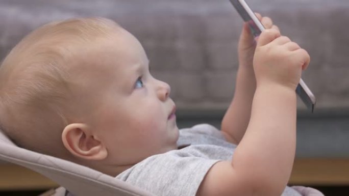 使用移动设备玩得开心的孩子，9个月大的男婴在平板电脑屏幕上观看俄罗斯儿童动画电视连续剧BabyRik
