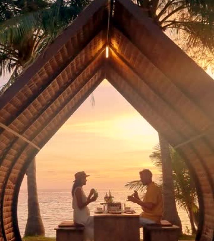 日落时分，一对男女在泰国麦岛的海滩上享用浪漫的晚餐