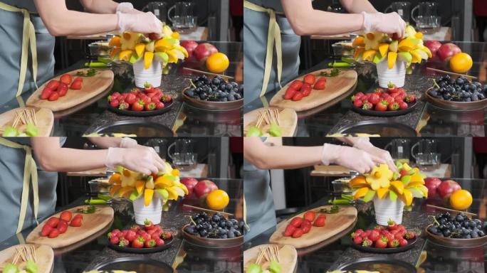 女孩通过将草莓粘在棍子上并将其推到另一个水果上，完成了水果花束的制作。美味的氛围