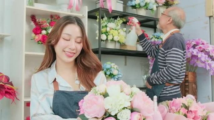 亚洲女花店企业家在花店布置一束鲜花。
