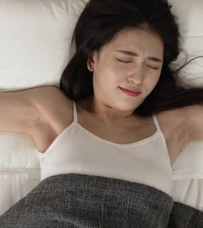 垂直屏幕: 顶视图有吸引力的亚洲中国女人从良好的睡眠中自然醒来，在一个和平的早晨，她在床上伸展手臂，