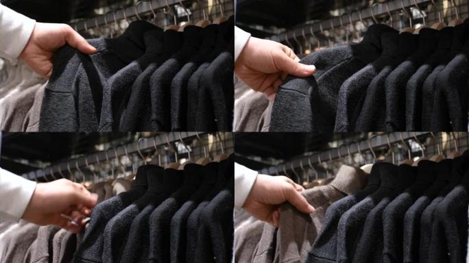 一个男人在零售商场选择挂在衣架上的衣服。