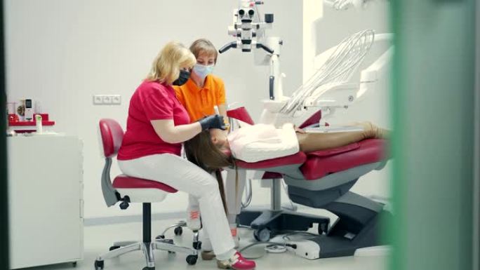 资深经验丰富的女牙医在牙科诊所用现代设备填充运河。通道的密封