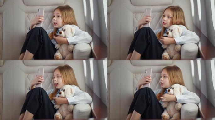 可爱的小女孩和泰迪熊在智能手机上聊天，坐飞机旅行。