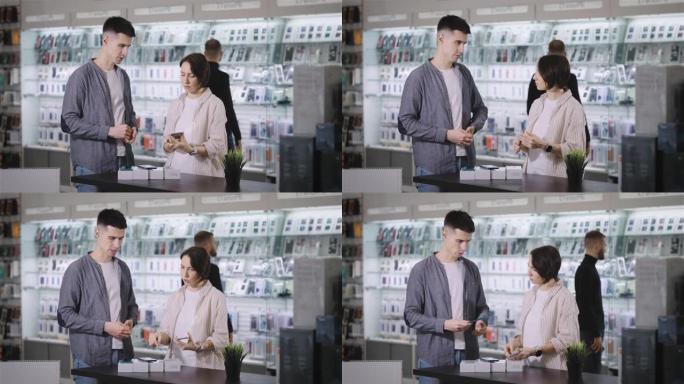 在小工具商店。一名男性顾问向一名年轻女性展示新款智能手机。