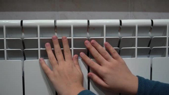 孩子们的手在温暖的家庭散热器附近热身。