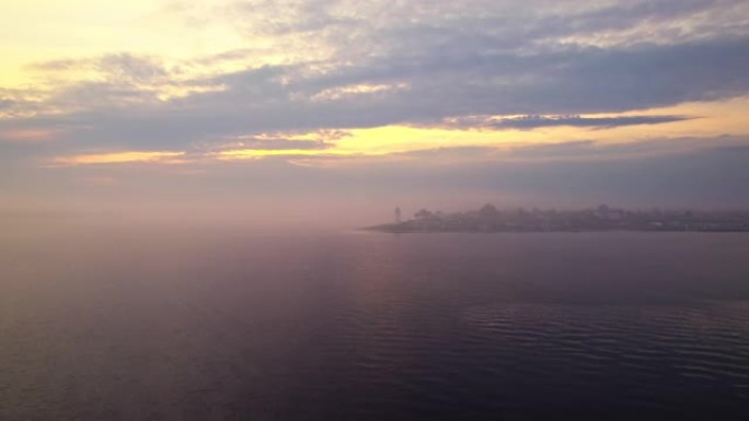 日落时，无人机在平静的海面上驶向灯塔