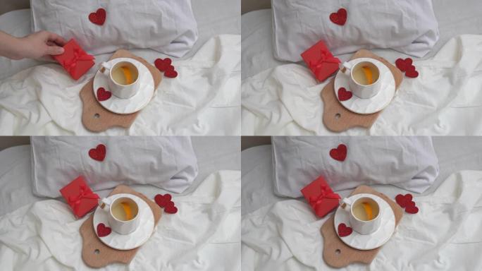 在床上吃早餐，用心喝杯绿茶，手放礼物。情人节或妇女节概念