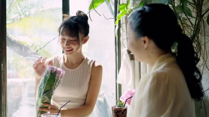 4k亚洲母女在咖啡店看着从街头市场购买的花束。