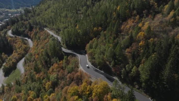空中无人机在秋天弯曲的山口上拍摄车辆