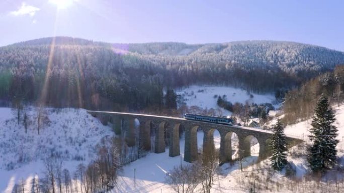 火车横穿一条石铁路高架桥，从左到右，冬季景观。