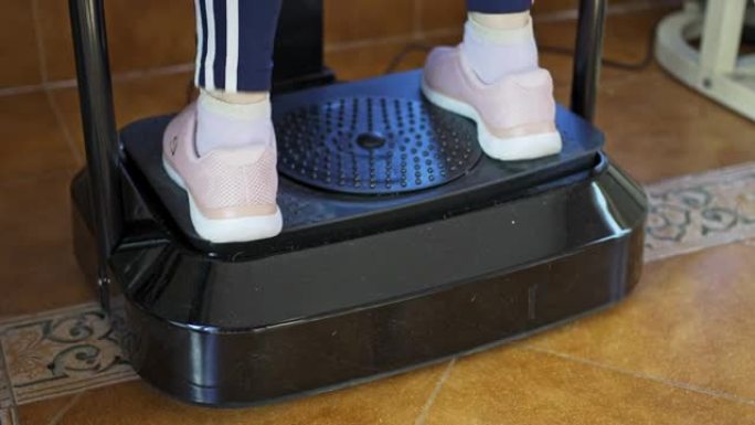 女子脚在振动体操机上的特写镜头，用于在家运动。