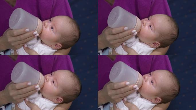昏昏欲睡的婴儿在瓶子里喝完牛奶。吃饭时，母亲怀里的小孩逐渐入睡。特写。