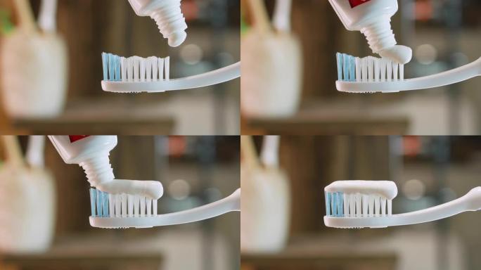 特写牙膏涂在白色牙刷上。浴室里的bokeh背景特写。牙齿清洁概念。从管子中挤出牙膏