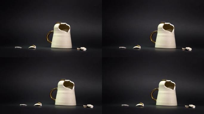 破碎的茶杯孤立在黑色背景上。破裂的咖啡杯和易碎的陶瓷片