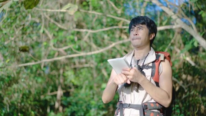 亚洲人类研究人员遍历使用双筒望远镜观察树木，树林中的鸟类，并在笔记本上写下信息以发展知识。在假期快乐