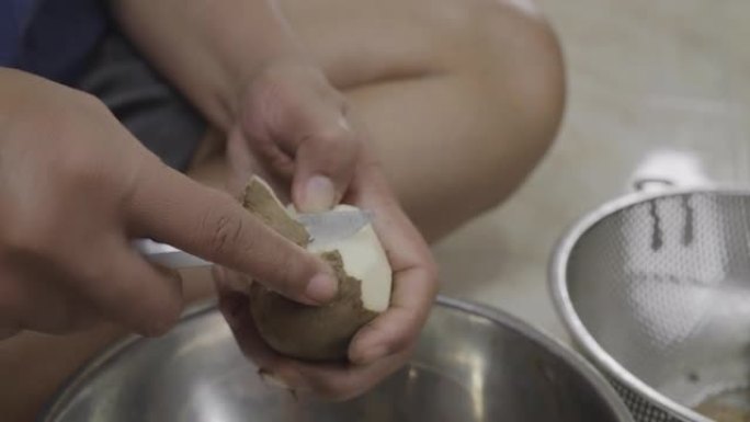 亚洲女性在家庭厨房脱皮薯蓣。食物制备概念。