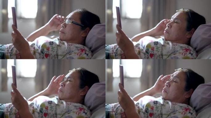 亚洲老年妇女因长时间盯着手机屏幕而感到疲劳。
