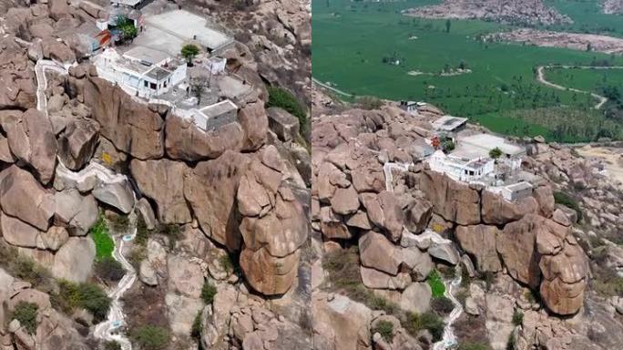 岩石巨石山空中拍摄的垂直视频，顶部是白色神庙，底部是田野