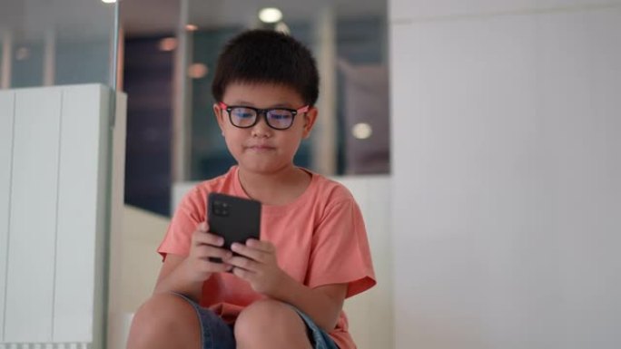 亚洲男孩使用智能手机上网，在日常生活中玩游戏