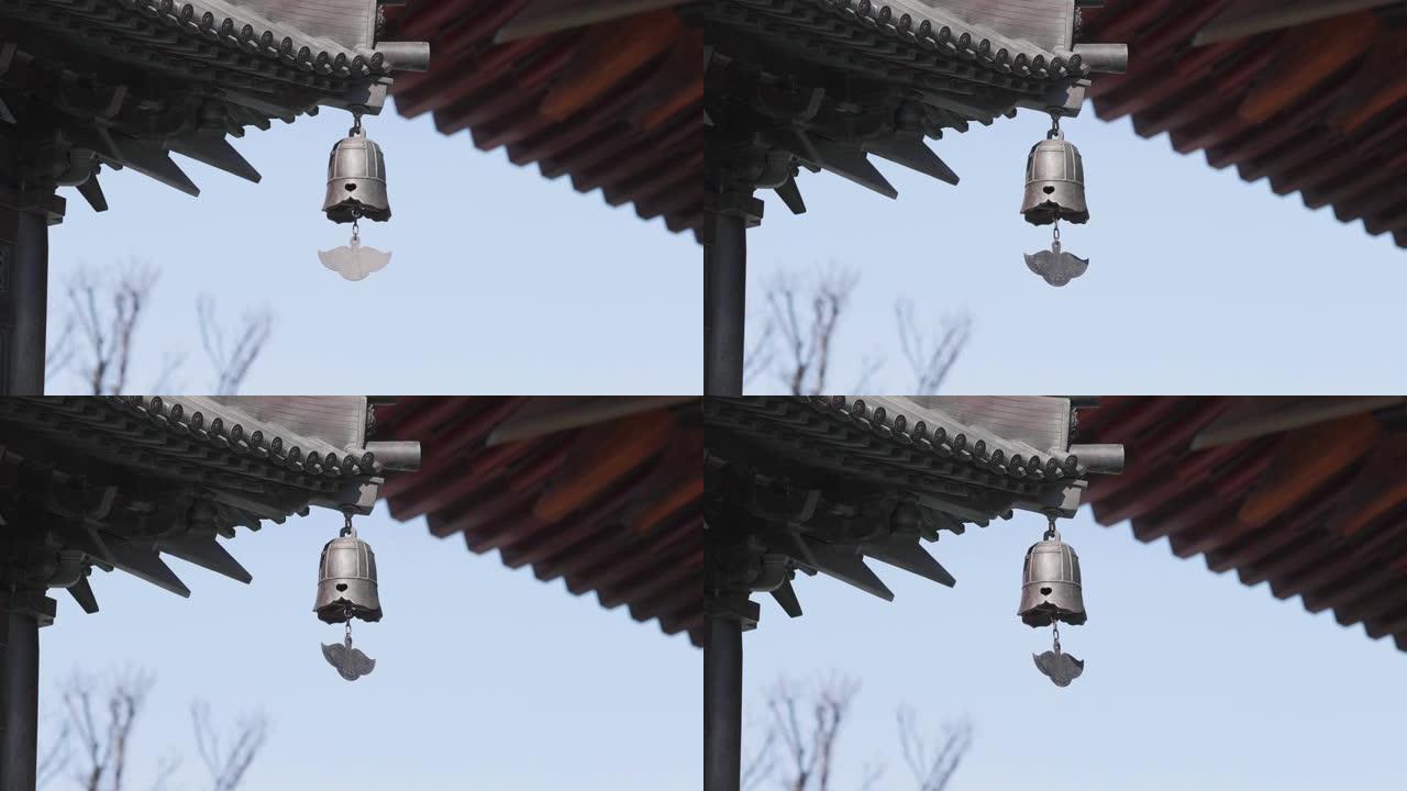 近距离的青铜钟摇摆在风与寺庙建筑的背景，4k慢动作镜头。