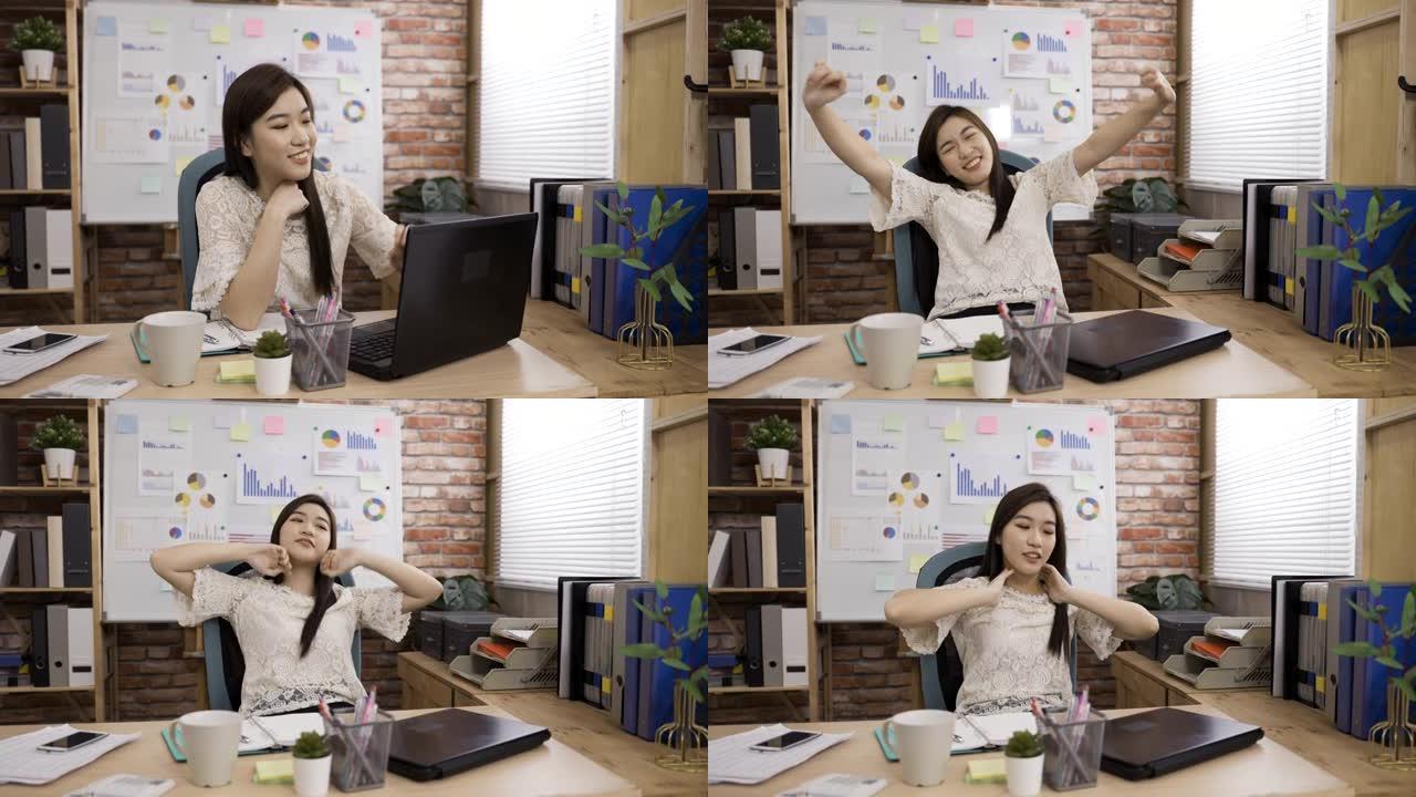 亚洲女性创意工作者关闭笔记本电脑正在锻炼她的颈部肌肉，伸展身体，对在办公室完成工作感到高兴。