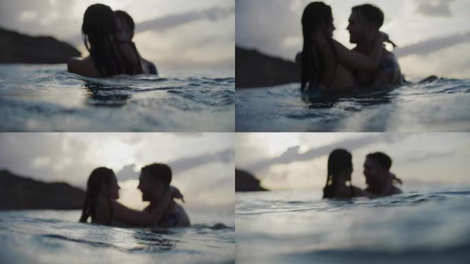 浪漫的异性恋情侣一起在金色日落时在海里游泳。接吻