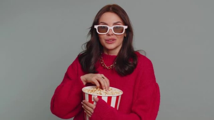 戴着3D眼镜的兴奋女人吃爆米花，看有趣的电视连续剧，体育游戏电影