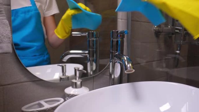 水龙头用黄色手套和蓝色织物清洗。