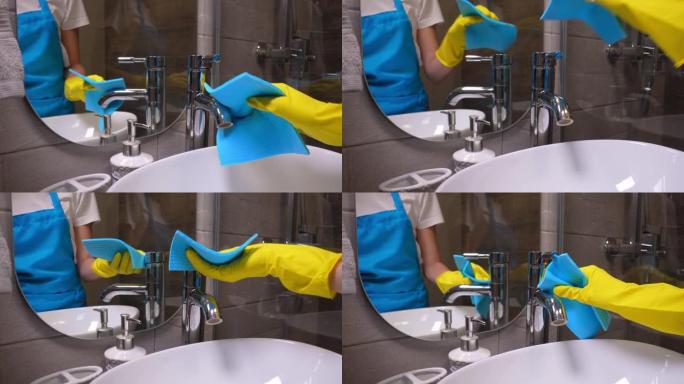 水龙头用黄色手套和蓝色织物清洗。