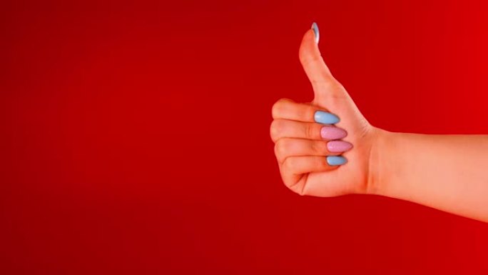 女人的手在红色背景上显示拇指，并有文字空间。无法识别的人表现出类似的手势