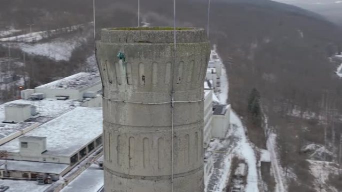 令人眼花winter乱的冬季近距离空中无人机视频，围绕旧的废弃工业混凝土烟囱向左移动。