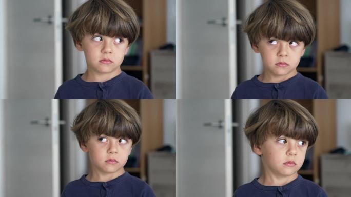 一个沉思的小男孩侧身思考的肖像。近距离面对站在室内的孩子，表情沉思