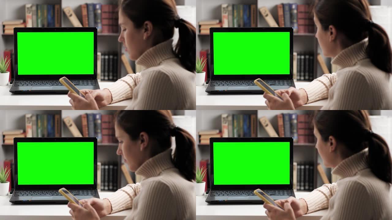 女人坐在桌子旁，看着绿屏笔记本电脑，她输入屏幕键盘并在internet上进行在线视频连接。色度键电脑