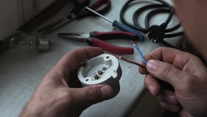 电工大师将电线连接到电灯插座。节电概念