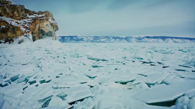 贝加尔湖，飞越冰屑，蓝色的雪峰。山脊和背景中的黄色岩石。俄罗斯西伯利亚贝加尔湖。无人机航拍4k