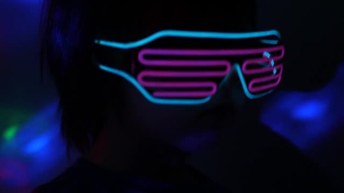 男孩在霓虹灯眼镜的迪斯科舞厅跳舞，在虚拟现实中的metaverse中玩耍