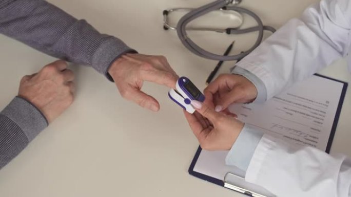 护士用手指脉搏血氧仪测量患者的血氧饱和度