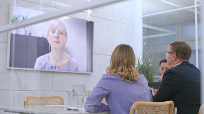 会议室里的LD人与一名妇女进行视频会议