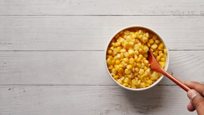 勺子在桌子上的碗里摘甜玉米，