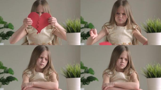 心烦意乱的孩子抱着两张红纸的心，心碎和心痛的概念。愤怒的小女孩在情人节单身。心碎，失去爱。争吵刹车概