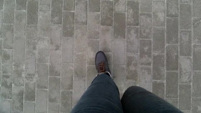 穿着灰色裤子和棕色冬靴的女人腿沿着人行道行走 -- 俯视图。视频9秒