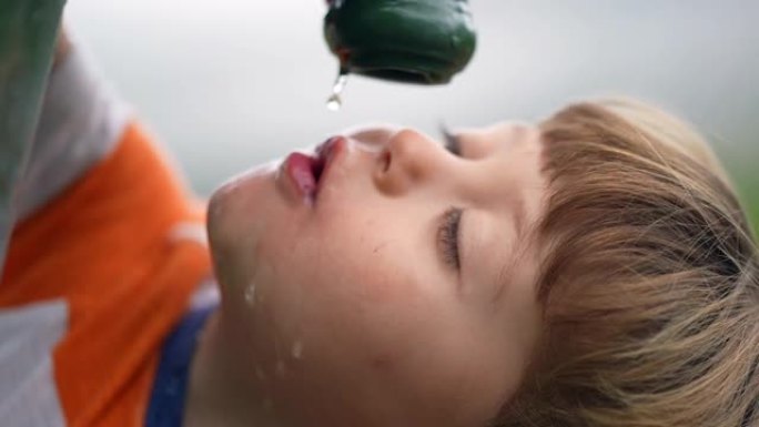 口渴的孩子在公园用水龙头喝水。一个小男孩在慢动作特写镜头中补水饮料