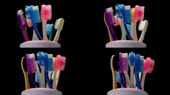玻璃牙刷的特写镜头在黑色背景上旋转。护理牙齿，五彩牙刷。转盘上的牙刷