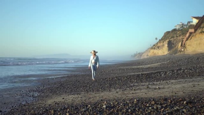 年轻的拉丁裔妇女在空旷的卵石海滩上享受孤独